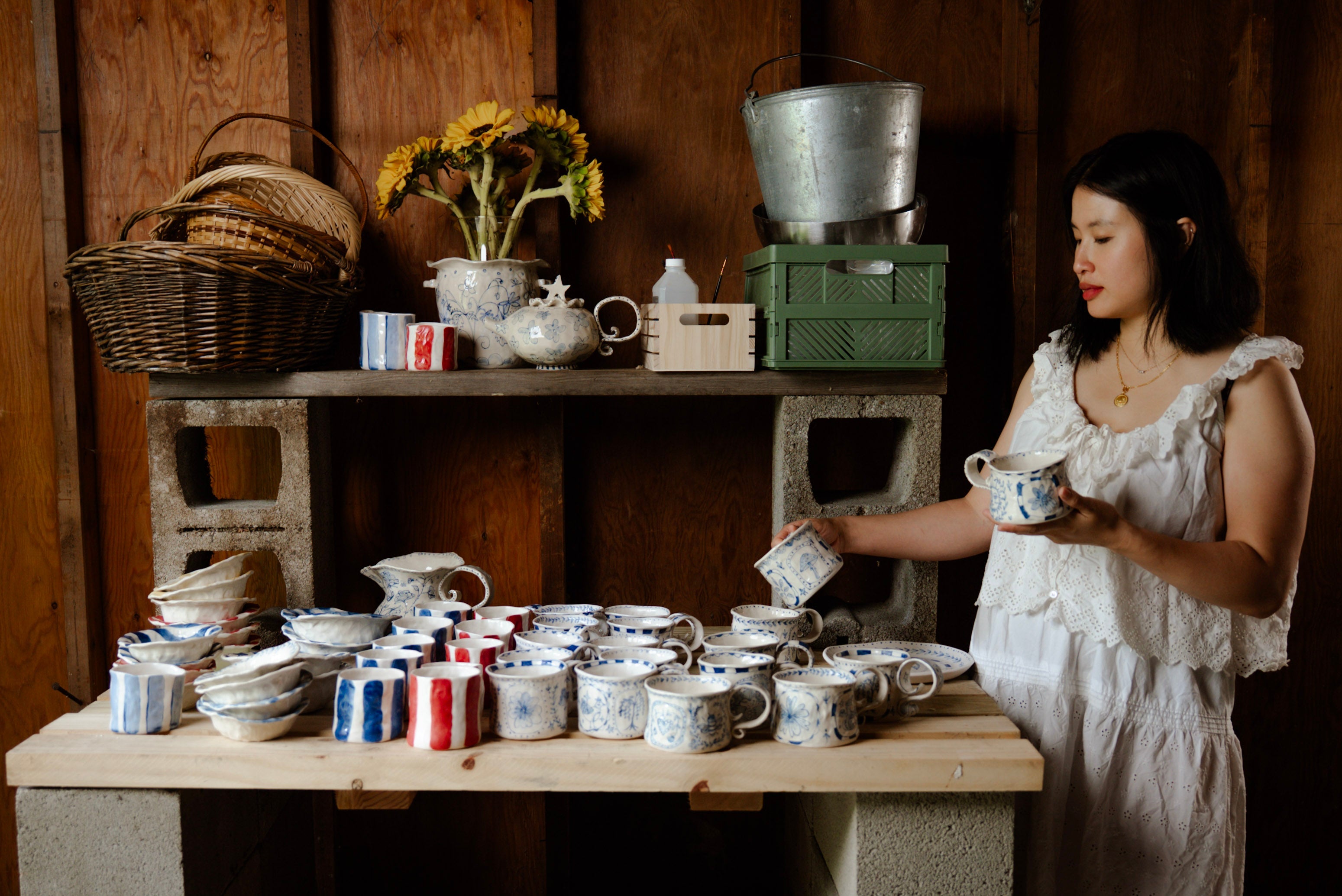 Val Chan Eldridge next to a table of her ceramics