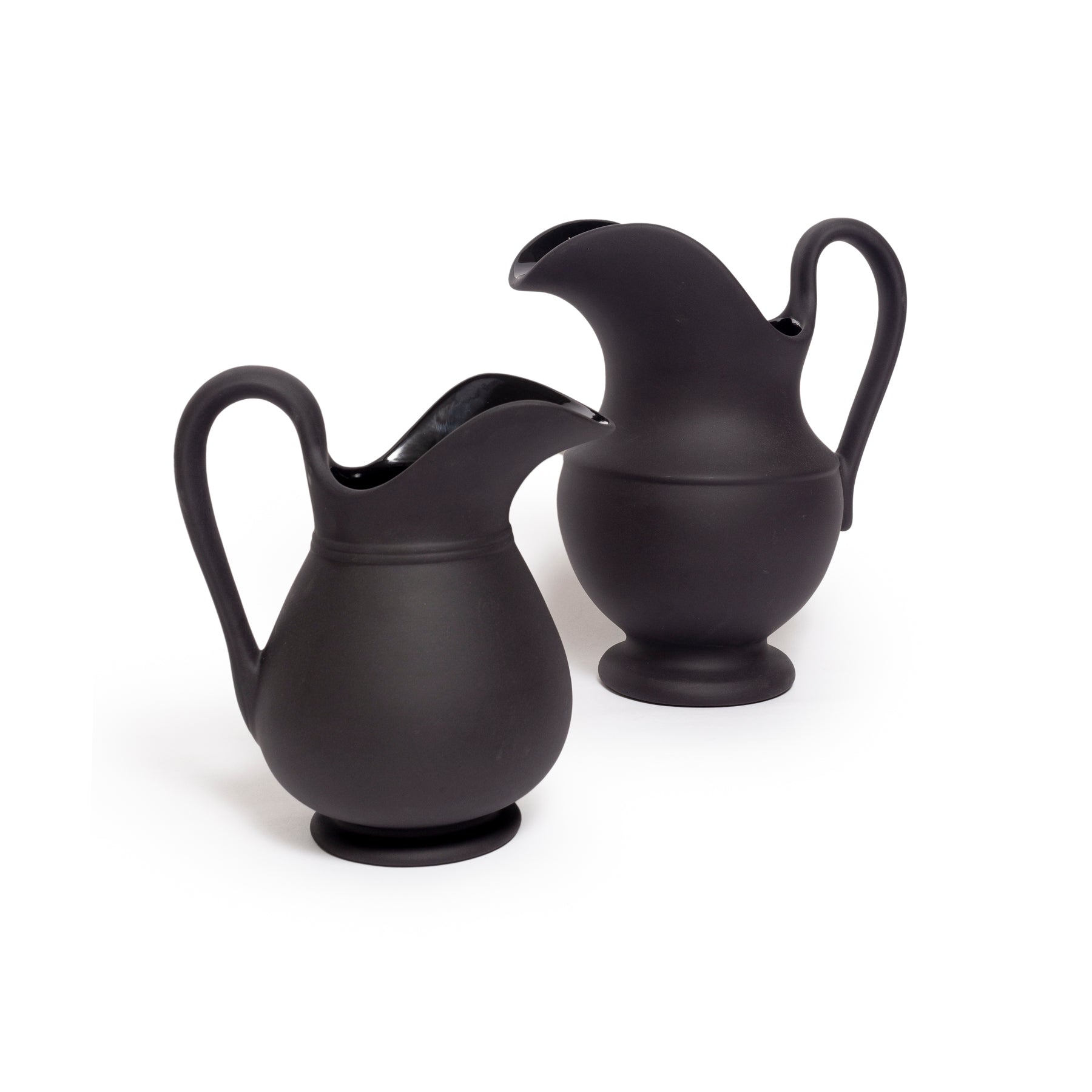 Two black ceramic pitchers on a white background