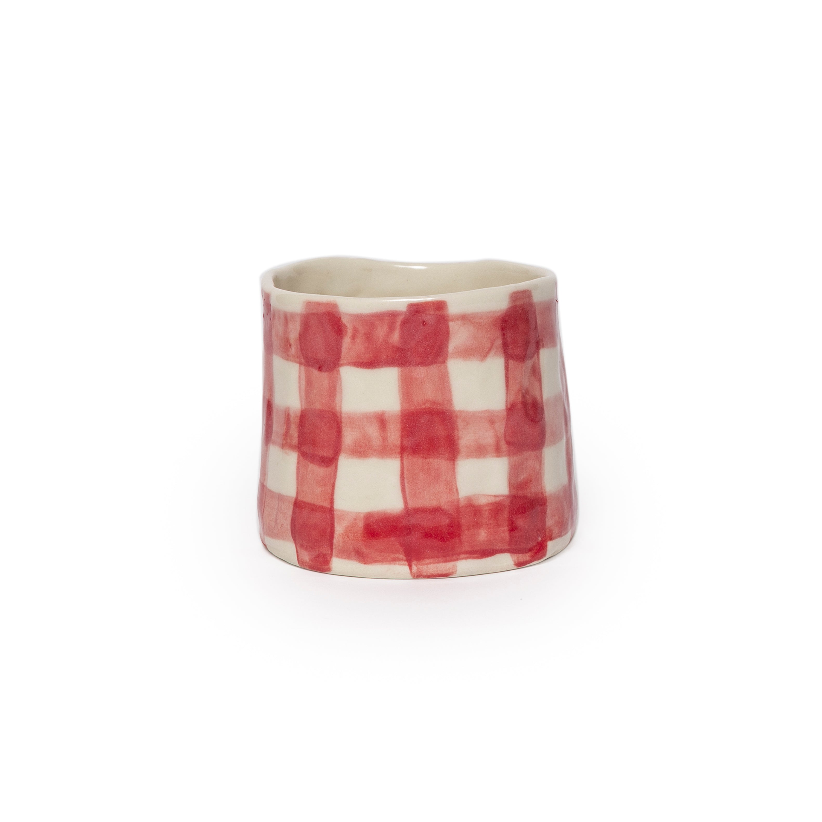 Ceramic cup with red and white checkered pattern on a white background